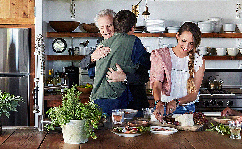 A family greeting their dad in a rustic farmhouse kitchen.